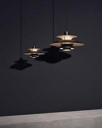 Black and gold pendant lights arranged in a dark modern interior, showcasing an elegant minimalist lighting style.