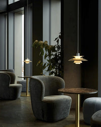 Small pendant light displayed in a dark modern room with lounge chairs and indoor plants.