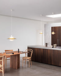 White pendant light hanging above a dining table in a bright modern kitchen and dining area.