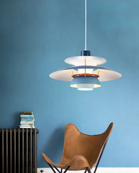Blue and white layered pendant light displayed against a blue wall with a modern chair and interior accents.