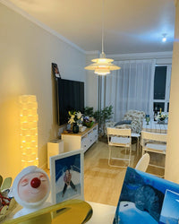 Modern white pendant light with layered shades installed in a contemporary living space, adding a stylish focal point above the dining area.