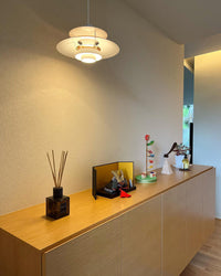 White layered pendant light hanging above a modern console cabinet with minimalist decor and warm interior lighting.