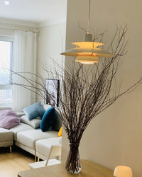 Modern white pendant light with layered shades installed above a console table, adding an elegant lighting accent to a contemporary interior space.