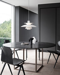 White pendant light above a table in a modern workspace or dining area with minimalist furniture.